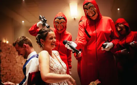 Une mariée hilare, un micro tendu par un personnage masqué rouge. Une scène inattendue pour un mariage surprise.