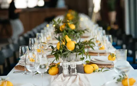 Un élégant nom de table mariage orné de citrons frais et de verdure. Les verres à vin et les assiettes sont dressés, prêts pour un festin ensoleillé.