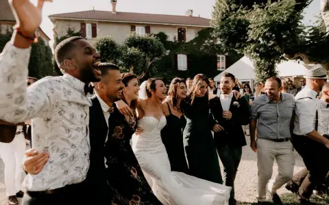 Un groupe d'amis danse joyeusement, la mariée en robe blanche au milieu. Une scène de mariage pleine de vie, avec une ambiance de parole chanson mariage rigolote.