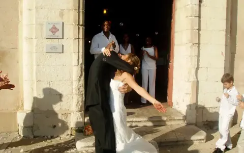 Mariage à l'église : le couple s'embrasse devant l'édifice, entouré d'invités joyeux. La musique du mariage résonne.