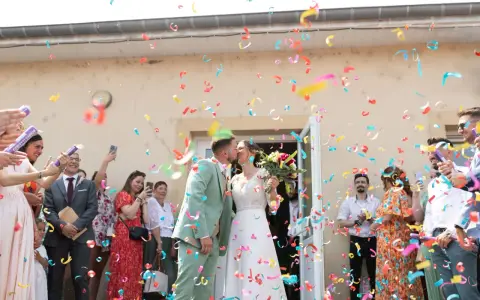 Des confettis colorés pleuvent sur les jeunes mariés qui s'embrassent. Une joyeuse tradition pour célébrer leur union.