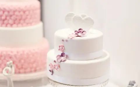 Deux pièces montées, l'une blanche décorée de cœurs et fleurs, l'autre rose texturée. Le coût d'une pièce montée peut varier.