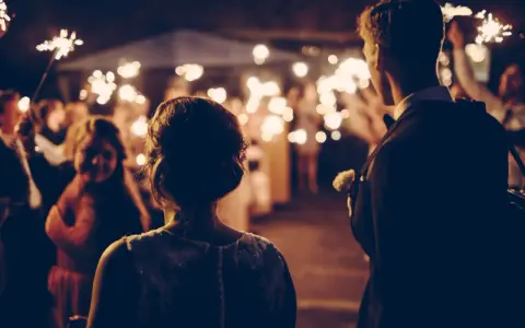 Couple au milieu d'une foule tenant des feux de Bengale, ambiance magique pour ce mariage sans dj.