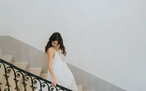 Une mariée descend un escalier, sa robe blanche fluide. Un moment clé pour comment choisir sa robe de mariée.