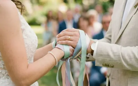 Mains jointes, rubans pastel noués, symbole d'un rituel d'union. Le couple célèbre son amour.