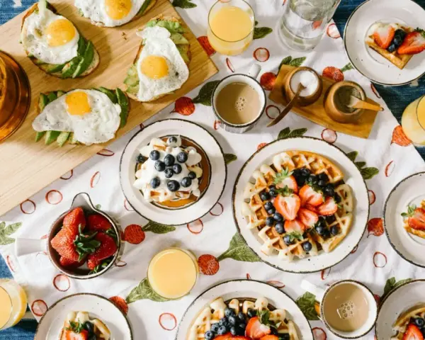 Un délicieux brunch de mariage : gaufres aux fruits, toasts avocat-œuf, jus d'orange et café. Une idée parfaite pour célébrer !