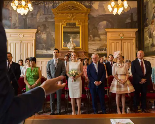 Le couple se tient au centre, entouré de leurs 5 témoins mariage. La mariée porte une robe blanche et tient un bouquet. Les invités sont élégamment vêtus.