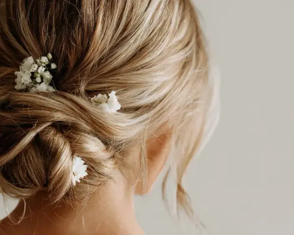 Coiffure invitée mariage boheme : un chignon flou orné de petites fleurs blanches, parfait pour une allure romantique et décontractée.