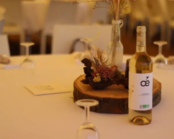 Bouteille de vin blanc sur une table de mariage, avec une décoration florale et des verres. La quantité d'alcool fort est modérée pour célébrer.