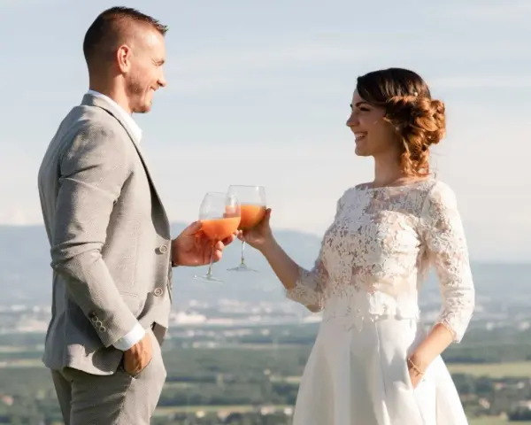 Un couple marié trinque avec des cocktails fruités, une belle quantité de soft pour un mariage en plein air.