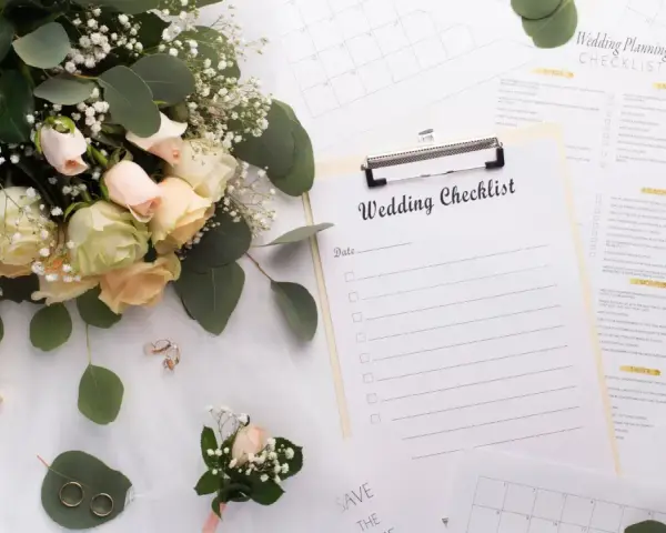 Un bouquet de roses, des alliances et une liste de mariage pour organiser son mariage soi-même.