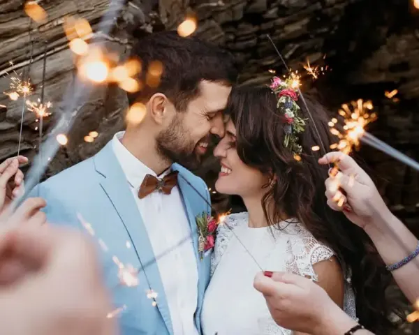 Un couple s'embrasse tendrement, entouré de feux de Bengale, lors de leur entrée pour une cérémonie laïque joyeuse.
