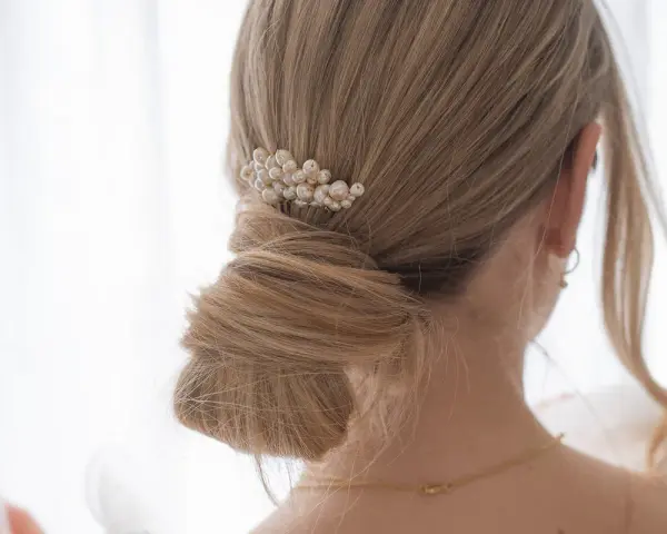 Chignon mariage flou orné d'un peigne de perles. Une coiffure élégante pour le grand jour.