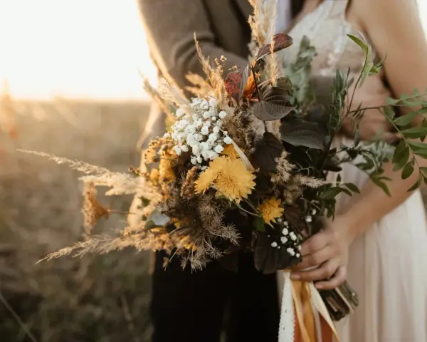 Un bouquet champêtre aux tons chauds, parfait pour des cadeaux invités mariage fait maison. Des herbes de la pampa, des fleurs jaunes et des feuilles sombres.
