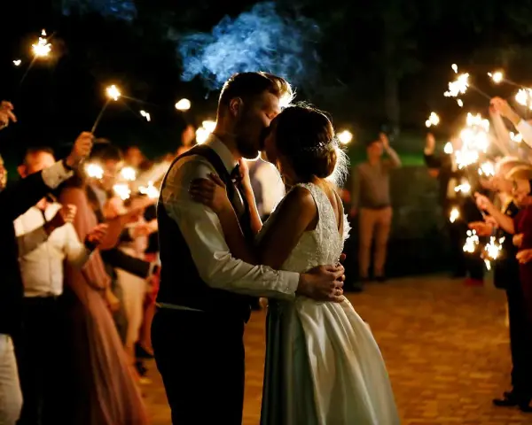 Un couple s'embrasse sous des feux de Bengale, entouré de leurs invités. Une belle idée d'animation mariage témoin pour un moment magique.