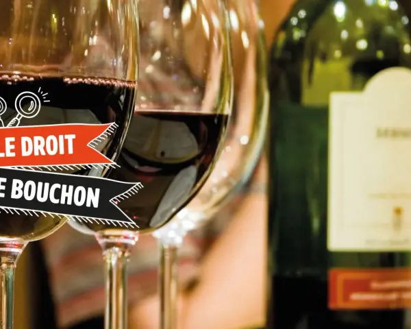 Verres de vin rouge, une bouteille et une bannière "Le Droit de Bouchon". Le prix est une question à explorer.