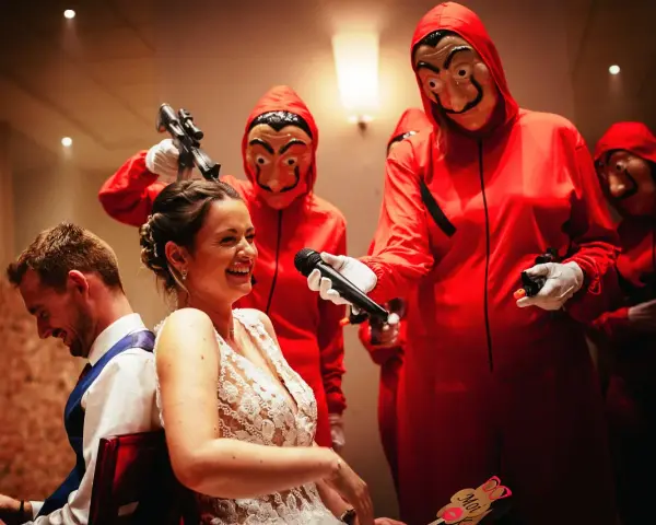 Une mariée hilare, un micro tendu par un personnage masqué rouge. Une scène inattendue pour un mariage surprise.