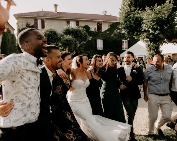 Un groupe d'amis danse joyeusement, la mariée en robe blanche au milieu. Une scène de mariage pleine de vie, avec une ambiance de parole chanson mariage rigolote.