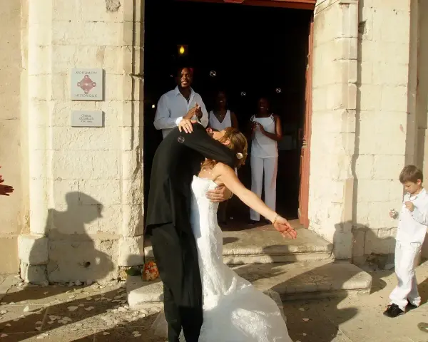 Mariage à l'église : le couple s'embrasse devant l'édifice, entouré d'invités joyeux. La musique du mariage résonne.