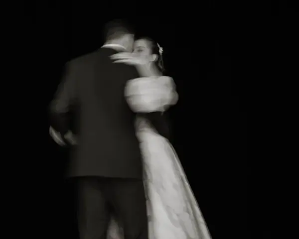 Un couple danse lors de l'ouverture de bal de leur mariage, le mouvement capturé dans un flou artistique.