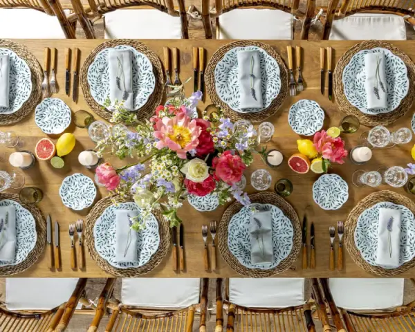 Plan de salle mariage table ronde : une table en bois dressée avec des assiettes fleuries, des verres en cristal, des fruits et des bouquets de fleurs.