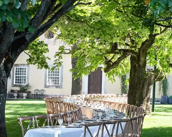 Table dressée dans un jardin luxuriant pour un quinta mariage Portugal. Ambiance champêtre sous les arbres.