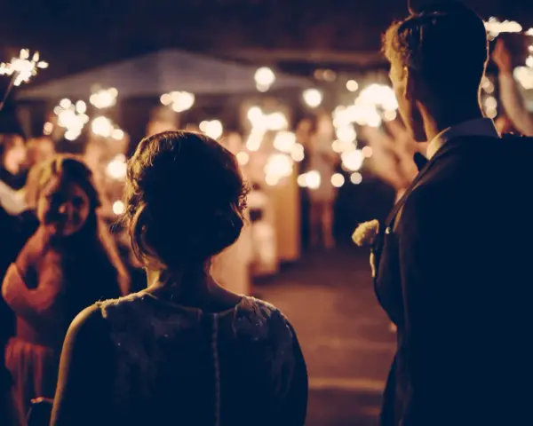Couple au milieu d'une foule tenant des feux de Bengale, ambiance magique pour ce mariage sans dj.