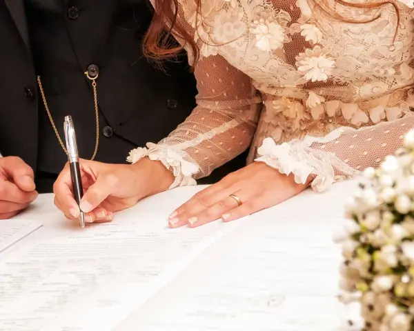 La mariée signe l'acte de mariage, un moment clé de la tradition mariage français. La bague au doigt symbolise leur union.