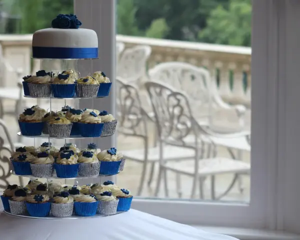 Magnifique pièce montée de cupcakes bleus et blancs, décorée de roses en sucre.