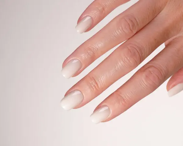 Main d'une mariée avec un french manucure spécial mariage, aux ongles laqués d'un blanc nacré, prêts pour le grand jour.