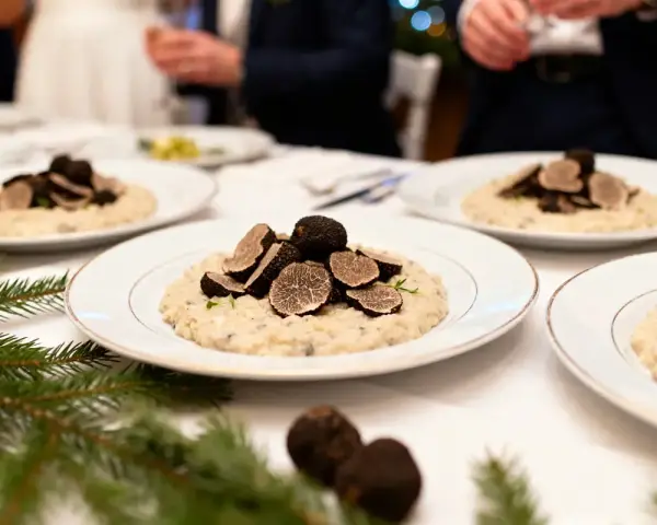Un délicieux repas mariage hiver : des assiettes de risotto aux truffes noires, garnies de fines lamelles, sur une table dressée avec des branches de sapin.