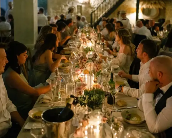 Un dîner de mariage réussi, avec une longue table dressée, des bougies, des fleurs et des invités souriants.