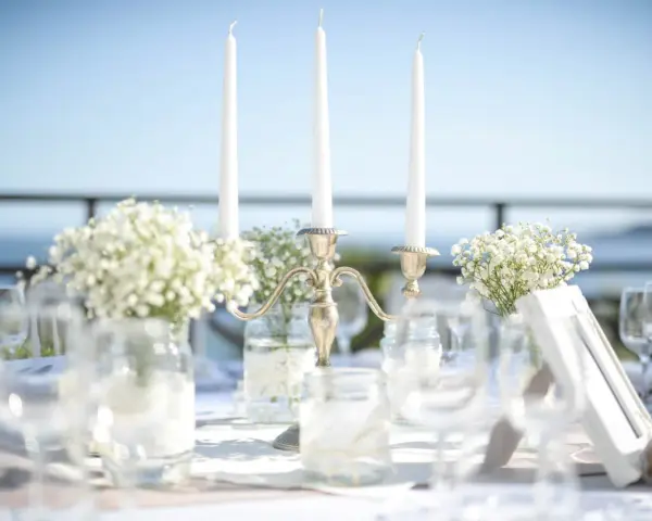 Décoration de mariage : bougies, fleurs et verres sur une table. La distance entre 2 tables mariage est suggérée par l'agencement.
