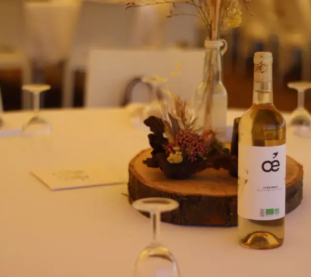 Bouteille de vin blanc sur une table de mariage, avec une décoration florale et des verres. La quantité d'alcool fort est modérée pour célébrer.