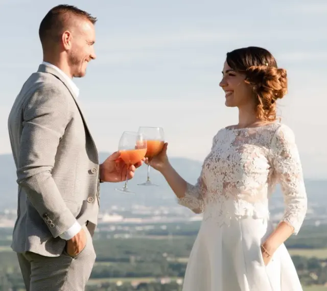 Un couple marié trinque avec des cocktails fruités, une belle quantité de soft pour un mariage en plein air.
