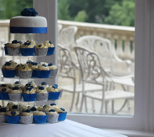 Magnifique pièce montée de cupcakes bleus et blancs, décorée de roses en sucre.