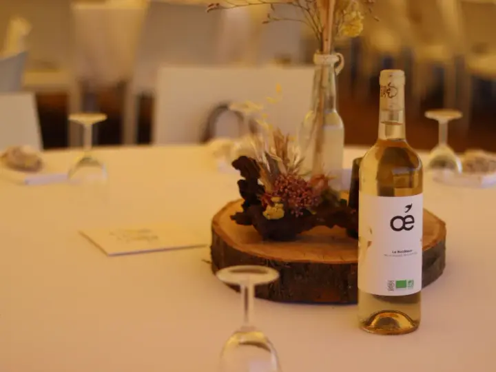 Bouteille de vin blanc sur une table de mariage, avec une décoration florale et des verres. La quantité d'alcool fort est modérée pour célébrer.