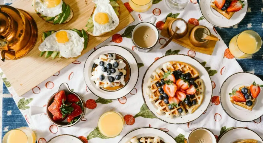 Un délicieux brunch de mariage : gaufres aux fruits, toasts avocat-œuf, jus d'orange et café. Une idée parfaite pour célébrer !