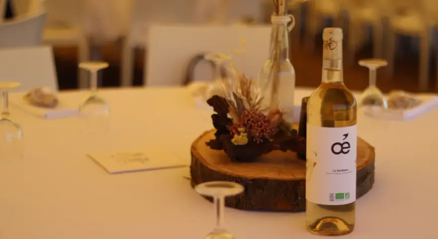 Bouteille de vin blanc sur une table de mariage, avec une décoration florale et des verres. La quantité d'alcool fort est modérée pour célébrer.