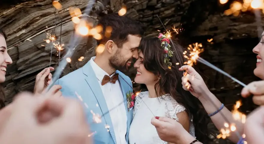 Un couple s'embrasse tendrement, entouré de feux de Bengale, lors de leur entrée pour une cérémonie laïque joyeuse.