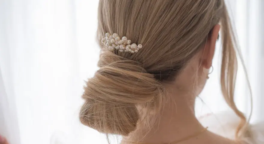 Chignon mariage flou orné d'un peigne de perles. Une coiffure élégante pour le grand jour.