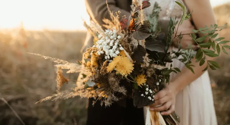 Un bouquet champêtre aux tons chauds, parfait pour des cadeaux invités mariage fait maison. Des herbes de la pampa, des fleurs jaunes et des feuilles sombres.