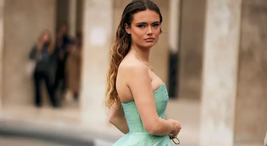 Une jeune femme en robe bustier vert menthe, parfaite pour savoir comment s'habiller pour un mariage. Cheveux longs ondulés, maquillage audacieux.
