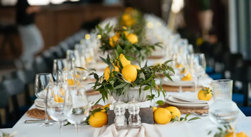 Un élégant nom de table mariage orné de citrons frais et de verdure. Les verres à vin et les assiettes sont dressés, prêts pour un festin ensoleillé.
