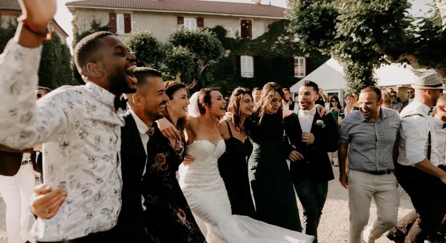 Un groupe d'amis danse joyeusement, la mariée en robe blanche au milieu. Une scène de mariage pleine de vie, avec une ambiance de parole chanson mariage rigolote.