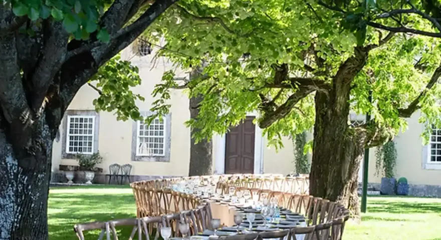 Table dressée dans un jardin luxuriant pour un quinta mariage Portugal. Ambiance champêtre sous les arbres.