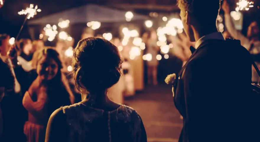 Couple au milieu d'une foule tenant des feux de Bengale, ambiance magique pour ce mariage sans dj.