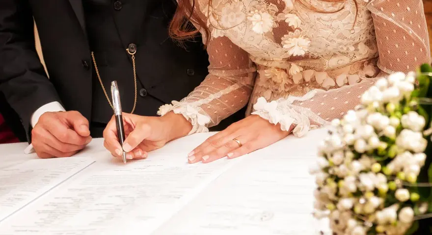 La mariée signe l'acte de mariage, un moment clé de la tradition mariage français. La bague au doigt symbolise leur union.