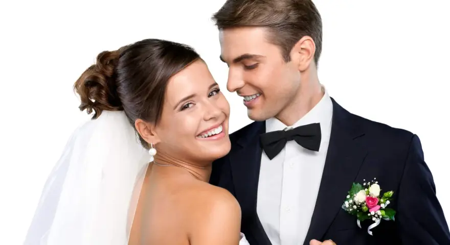 Un jeune couple marié, souriant et complice. La mariée, voile sur la tête, et le marié, nœud papillon, se préparent pour la fête. Combien donner à un mariage cousin ?