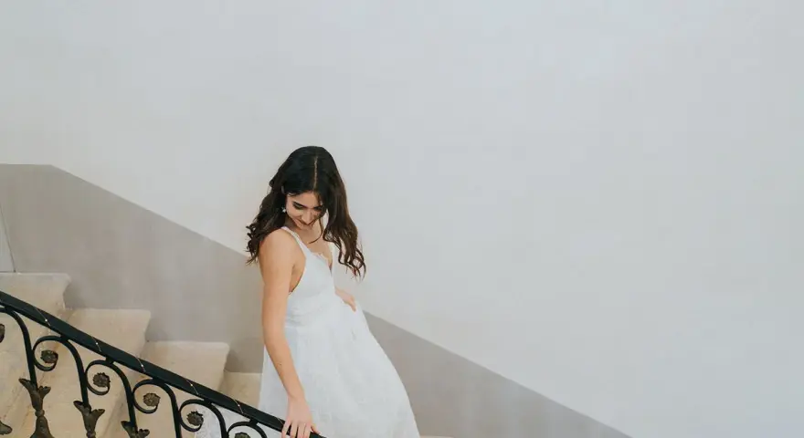 Une mariée descend un escalier, sa robe blanche fluide. Un moment clé pour comment choisir sa robe de mariée.